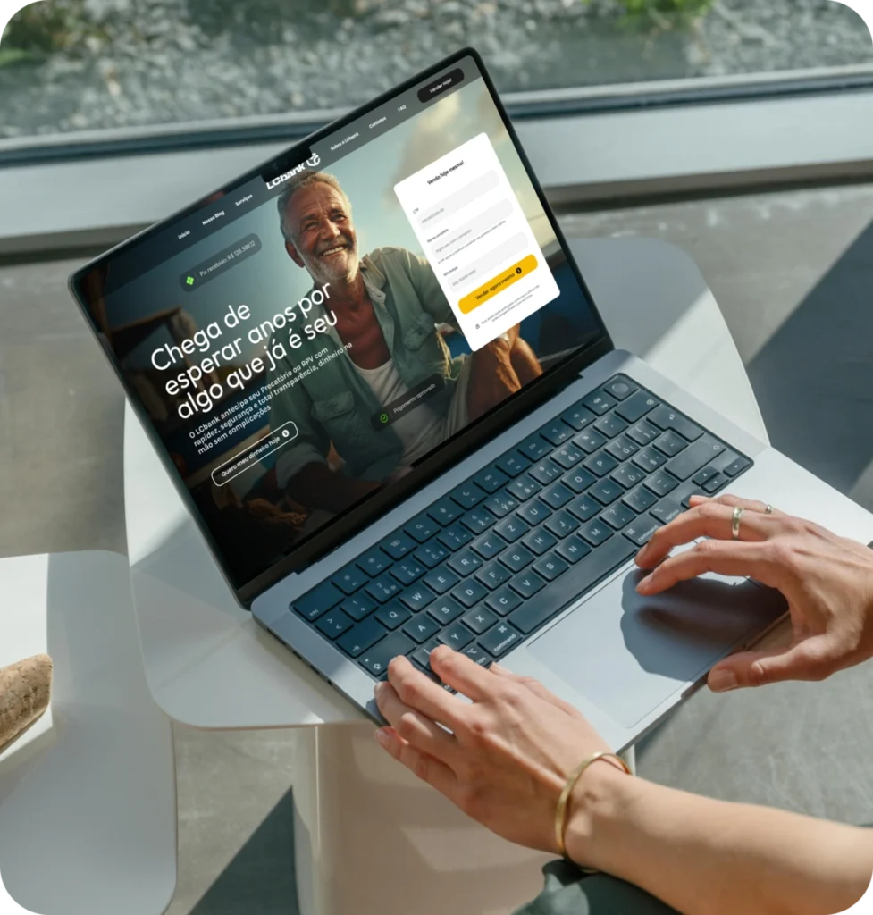 Laptop com tela do LCbank exibindo página inicial e homem sorrindo.